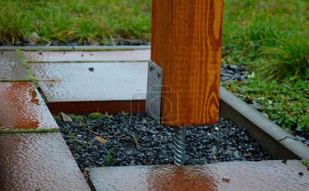 Foto de Fijar la viga de pérgola a la base de acero. el pie en forma de U, terminado con un alambre de hormigón, entra en el suelo de pavimentación - Imagen libre de derechos