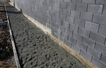 laying concrete paving in a lane between curbs. the edges of the tile cubes must be shortened and fit into the gaps. reciprocating saw. laying gravel, paving, cycle path, landscaping and earthworks