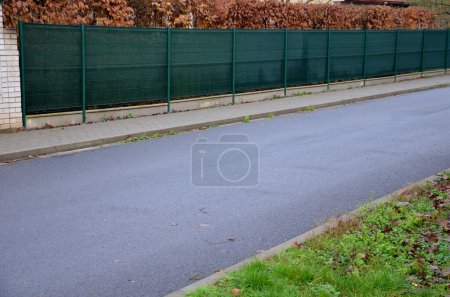 Téléchargez les photos : Le tissu d'ombrage sur la clôture métallique crée un espace privé et en un instant, vous avez une clôture opaque de voisins ennuyeux et des vues de la rue, chantier de construction, haie de corne d'asphalte - en image libre de droit