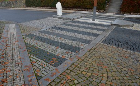 Téléchargez les photos : Pedestrian crossing with dividing island between lanes. arches with road markings planted with dry-loving flowers along the street. gardening. luxurious stone curbs and paving of the promenade - en image libre de droit