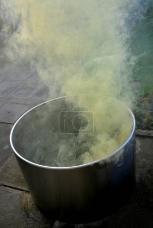Photo for Hot sulphurous spa treatments, in a stainless steel barrel from which yellow steam rises. flower pot flue. special effects on the terrace by the house. jetted circular bathtub. outdoor bathroom - Royalty Free Image