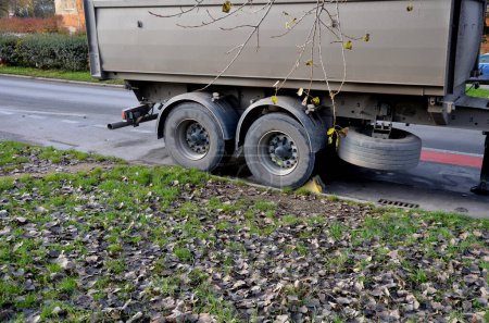 Téléchargez les photos : Une remorque de camion sale est garée dans la rue, elle a une roue coincée. coin en plastique. le timon de la voiture est déconnecté du tracteur. il a deux essieux - en image libre de droit
