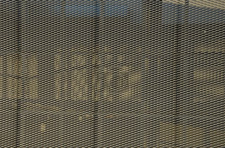 Foto de Revestimiento de acero de un edificio con una estructura de celosía metálica expandida. las redes grises galvanizadas protegen el edificio industrial. Cielo azul en contraste con un fondo plateado, escalera, laboratorio, ciencia - Imagen libre de derechos