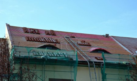 réparation du toit historique en cours de reconstruction. carreaux de contrainte brûlés sont prêts en pieux pour la pose sur des lattes de toit. bâtiment historique baroque avec échafaudage et grue à échelle, avec plate-forme de treuil