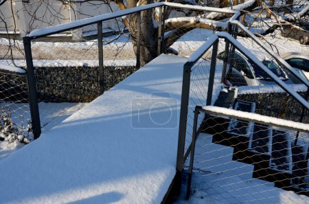 Photo for Construction of a steep staircase by stone wall car park with high durability even under heavy load galvanized steel floor grate and railings. gabion above him a wire fence. corridor, narrow, ramp - Royalty Free Image