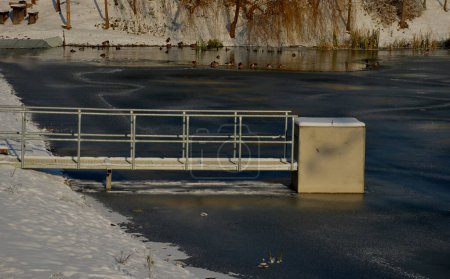 Téléchargez les photos : Pont sur le déversoir de sécurité du barrage. pont en pierre avec pavage naturel de pierres plates grises. sur le bord des murs de soutènement est une balustrade subtile en fer forgé de couleur. l'eau coule à travers - en image libre de droit