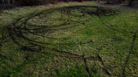 Foto de Evidence of damage to agricultural land by car skidding. the police use a drone to document the damage after youths rampage in cars on the meadow. ruts into circles from spinning tires, landscape - Imagen libre de derechos