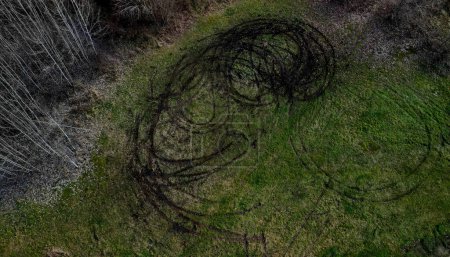 Foto de Evidence of damage to agricultural land by car skidding. the police use a drone to document the damage after youths rampage in cars on the meadow. ruts into circles from spinning tires, landscape - Imagen libre de derechos