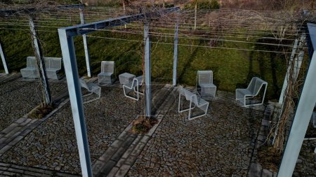 Photo for From metal constructions to climbing plants and vines is a sitting terrace of rough stone paving chipped cubes. metal gray furniture, benches, chairs, coffee. point of view, public park perennial - Royalty Free Image