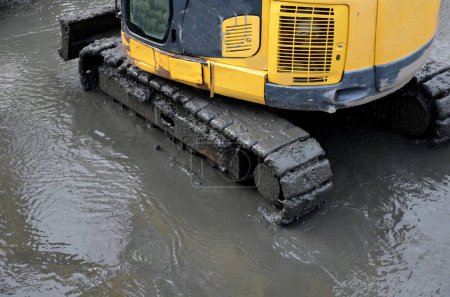 removing sedimentary sludge from the bottom of a pond or a swimming lake in the village. the muddy water cleaning set with pumps vacuums the sump. a crawler excavator cleans bottom from deposits soil 