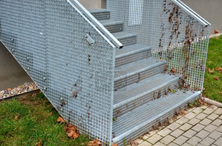 Photo for Stairs to a residential building made of stainless steel grid. galvanized stair grating made of expanded metal. lawn concrete sidewalk. - Royalty Free Image