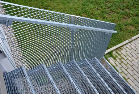 Photo for Stairs to a residential building made of stainless steel grid. galvanized stair grating made of expanded metal. lawn concrete sidewalk. - Royalty Free Image