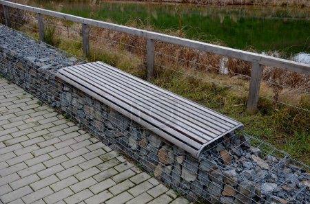 Téléchargez les photos : Swimming lake landscaped coastal zone of shallow water and a deeper part for swimming. fenced with wooden beams fence and gabion wall with plank benches. retention pond, tank, source, fire, dry - en image libre de droit