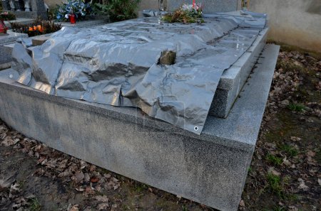 Photo for A grave covered with a gray tarpaulin is being renovated, or the stone slab is being replaced. exhumation of the dead for expert examination of the remains. suspicion of murder, poisoning - Royalty Free Image