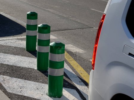 Photo for Plastic barriers in the form of plastic bollards. they have a preventive effect, but can be bent and possibly run over by car. man tries to bend his hand down to the ground. Ideal deterring vehicle - Royalty Free Image