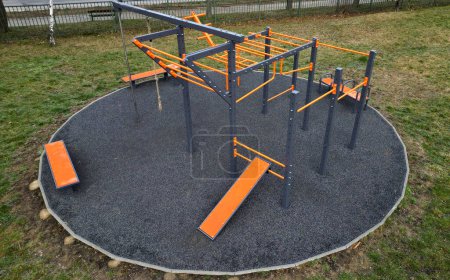 Photo for Fitness sports fields with stainless steel tools resemble torture tools with chains and handles. soft rubber surface sports ground outdoor gym. man holds a pulley and strengthens muscles - Royalty Free Image