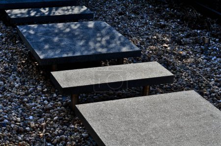 Steingänge über Wasserteiche auf Metallstreben schweben über gefrorenem Wasser. Gartenweg in einem Teich formalen oder japanischen Garten. rechteckige Platten aus Marmor, poliert