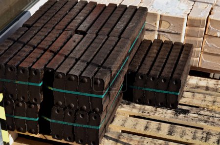 Photo for Briquettes stacked in bundles on a pallet. they are pressed into the shape of bricks and fit together well. kindling wood chips for the fireplace in mesh bags for supermarket sales - Royalty Free Image