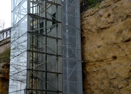Photo for An outdoor elevator with a glass structure can be added to a historic house where it is not possible to carry out demolition work. you can see the cabin going up the transparent shaft, rock, cliff - Royalty Free Image