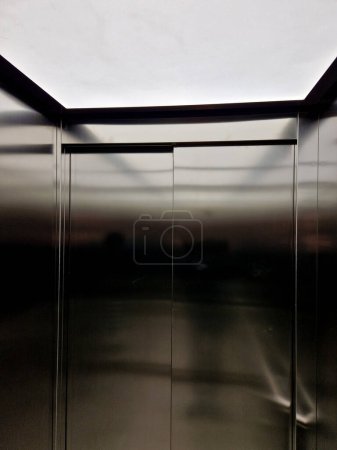 Téléchargez les photos : Intérieur de la cabine de l'ascenseur en acier inoxydable avec parquet en chêne et lambris miroir. main courante et siège inclinable pour personnes âgées et détente dans les bureaux de luxe, bois, bois - en image libre de droit