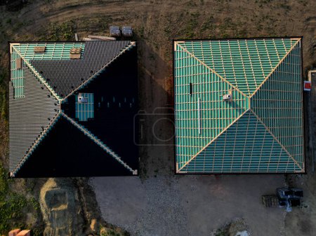 Photo for Construction site with several roofs in progress. Roofs with vapor-permeable foil. roof tiles are placed on the roof. concrete chimney passes through. approval quality control. view from above - Royalty Free Image