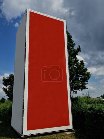 Photo for Metal structure shape of a block with stretched sails for placing printed advertising. An empty canvas is suitable for creating an inscription. red rectangle in the countryside by road, pillar - Royalty Free Image