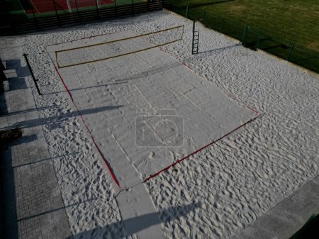Photo for White sand beach volleyball court. white soft dunes fenced with nets. The lines of the playing field are made of blue textile plastic straps, new, plowing, rolling, roller - Royalty Free Image