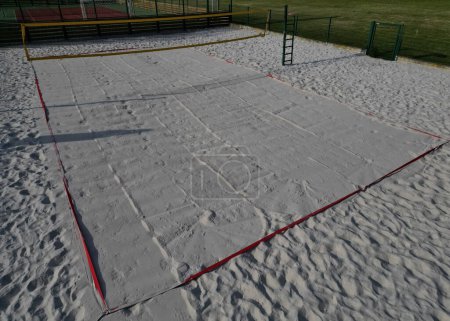 Photo for White sand beach volleyball court. white soft dunes fenced with nets. The lines of the playing field are made of blue textile plastic straps, new, plowing, rolling, roller - Royalty Free Image