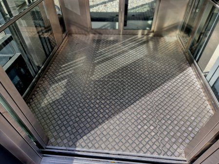Photo for Outdoor elevator with metal non-slip floor made of expanded metal. metal grid mesh shoe cleaning mat. interior, sunny, floor, exterior facade - Royalty Free Image