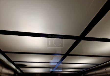 Téléchargez les photos : Le plafond de l'ascenseur ou du couloir est en plexiglas avec éclairage supérieur. le plafond est léger et en forme de grille carrée - en image libre de droit