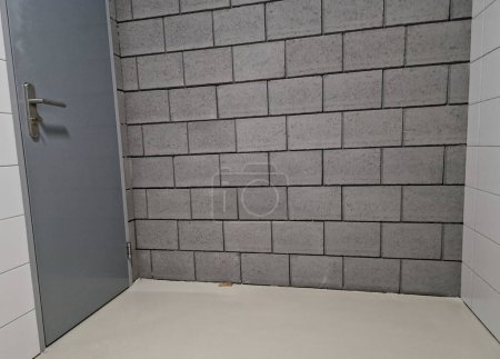 Foto de Bloques de hormigón gris de las paredes de un almacén de propósito construido con una puerta a un garaje de diseño austero - Imagen libre de derechos