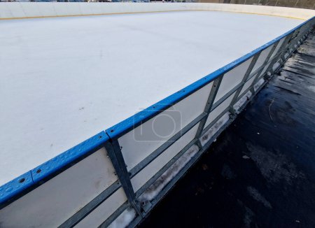 Téléchargez les photos : Hockey field with goalposts and yellow lines around perimeter. plastic barriers of children's ice rink with entrance to the ice through gate. rubber mat protects the blade of skate, blue edge - en image libre de droit