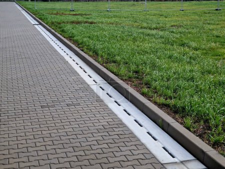 Photo for Slotted pipes drain rainwater and oil substances, drips from paved surfaces. concrete products at the curb interlocked paving tiles. sewage pipes hidden under the surface - Royalty Free Image