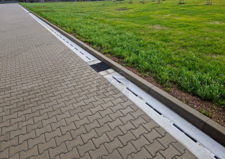 Photo for Slotted pipes drain rainwater and oil substances, drips from paved surfaces. concrete products at the curb interlocked paving tiles. sewage pipes hidden under the surface - Royalty Free Image