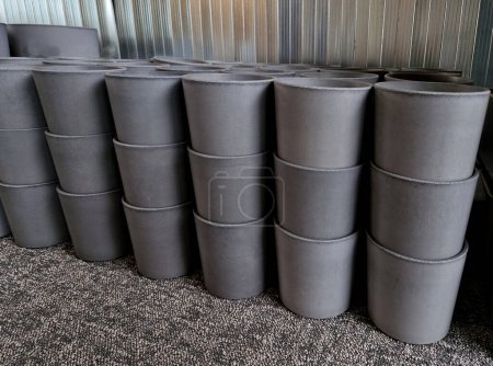 Photo for Gray concrete flower pots, lined up in a warehouse in rows for sale. plastic white tubs of bricks stacked on top of each other. production of cheap design containers for plants, carpet - Royalty Free Image