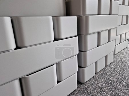 Photo for Gray concrete flower pots, lined up in a warehouse in rows for sale. plastic white tubs of bricks stacked on top of each other. production of cheap design containers for plants, carpet - Royalty Free Image