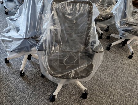 Photo for Furnishing the new office with chairs. wheeled swivel positioning medical chair protecting your back. plastic sheets cover the new classroom equipment until it is handed over to the customer - Royalty Free Image