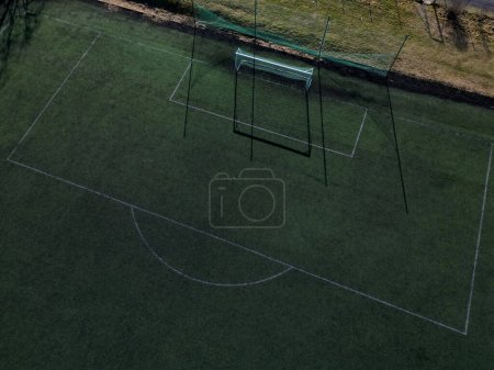 multifunctional outdoor playground for ball games at school. green artificial turf from a plastic carpet with lines. basketball hoops and soccer goals. around the grabbing high net and guardrails 
