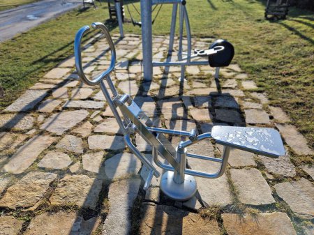 Photo for Fitness sports fields with stainless steel tools resemble torture tools with chains and handles. soft rubber surface sports ground outdoor gym. man holds a pulley and strengthens muscles, brown - Royalty Free Image