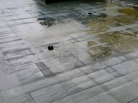Photo for Asphalt foil roof insulation is best tested by flooding it with water. rainwater drainage channels must work. regularly check clogged dirt grids. - Royalty Free Image