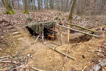 excavation of a house in a forest hollow. recessed cover with camouflage net for better concealment from enemy drones and aircraft. bushcraft cabin two against each other