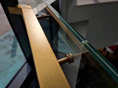 Téléchargez les photos : Bord du verre collé de la rambarde recouvert d'une bande en forme de U. garnitures transparentes de la rampe en tube d'acier inoxydable brillant plié. entrer dans le bâtiment - en image libre de droit