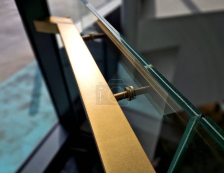  edge of the glued glass of the railing covered by a U-shaped strip. transparent fillings of the railing made of shiny stainless steel tube bent. step into the building