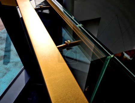  edge of the glued glass of the railing covered by a U-shaped strip. transparent fillings of the railing made of shiny stainless steel tube bent. step into the building