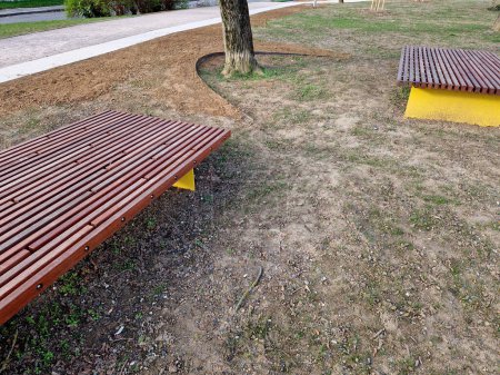 on the edge of the elevated terrace overlooking the park is a concrete long flowerpot with wood paneling and a rectangular bench. is part of the city promenade on the street and square