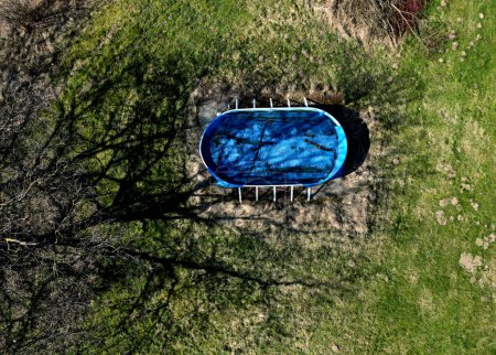 Foto de Jardín abandonado con una forma de piscina ovalada barata. descuidado apresuradamente comprado equipo de recreación es muy sucio y lleno de hojas en la primavera. es necesario iniciar el filtrado - Imagen libre de derechos