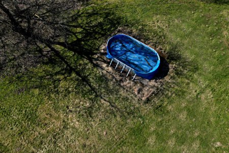 Foto de Jardín abandonado con una forma de piscina ovalada barata. descuidado apresuradamente comprado equipo de recreación es muy sucio y lleno de hojas en la primavera. es necesario iniciar el filtrado - Imagen libre de derechos