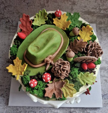 acorns, marshmallows and candied autumn leaves sit on top of a hunting-themed cake. vss is made by modeling from marzipan dough including moss and a mountain landscape with a deer, nature conservation