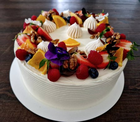 Photo for White cream cake with spirals and scalloped sides. fruit and flowers and cinnamon cure as a declaration of summer style - Royalty Free Image