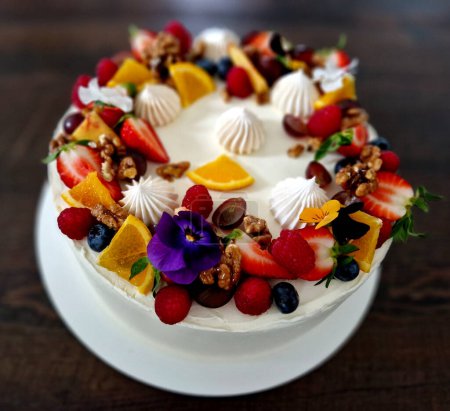 Photo for White cream cake with spirals and scalloped sides. fruit and flowers and cinnamon cure as a declaration of summer style - Royalty Free Image